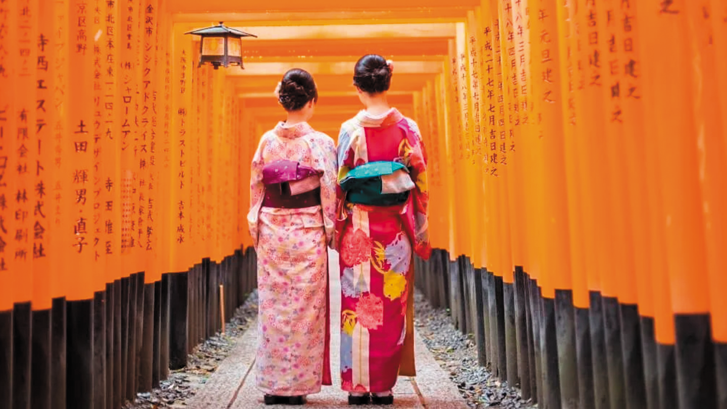 Fotografía de visitantes caminando a través de los toriis, arcos culturalmente representativos de Japón.